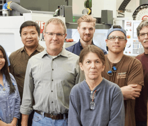A diverse group of ten individuals smiling in a workshop setting.